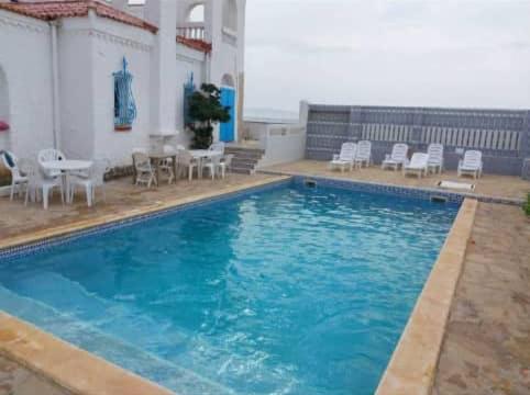 a large blue swimming pool with chairs and a table at Villa Marame in Bordj el Bahri