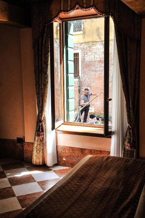 a man sitting in a window looking out of a building at Ca&#39; Amadi in Venice
