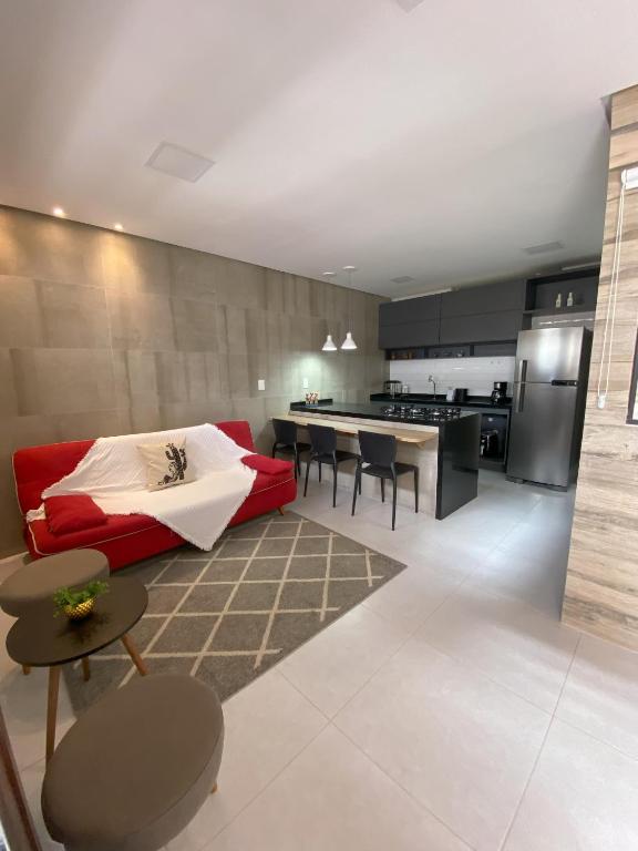 a living room with a red couch and a kitchen at Apartamento completo em Caruaru - 2 quartos - Conforto e ótima localização para famílias in Caruaru