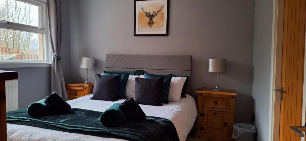 um quarto com uma cama com almofadas verdes em Ben Vorlich Cottage em Tarbet
