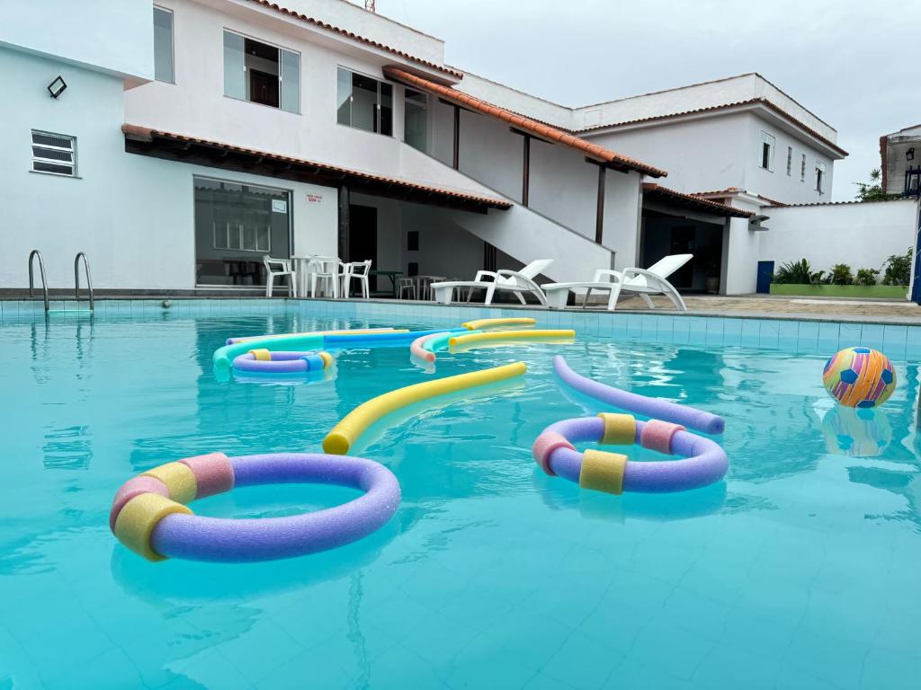 a swimming pool with inflatable tubes in the water at Pousada Natalli in Cabo Frio