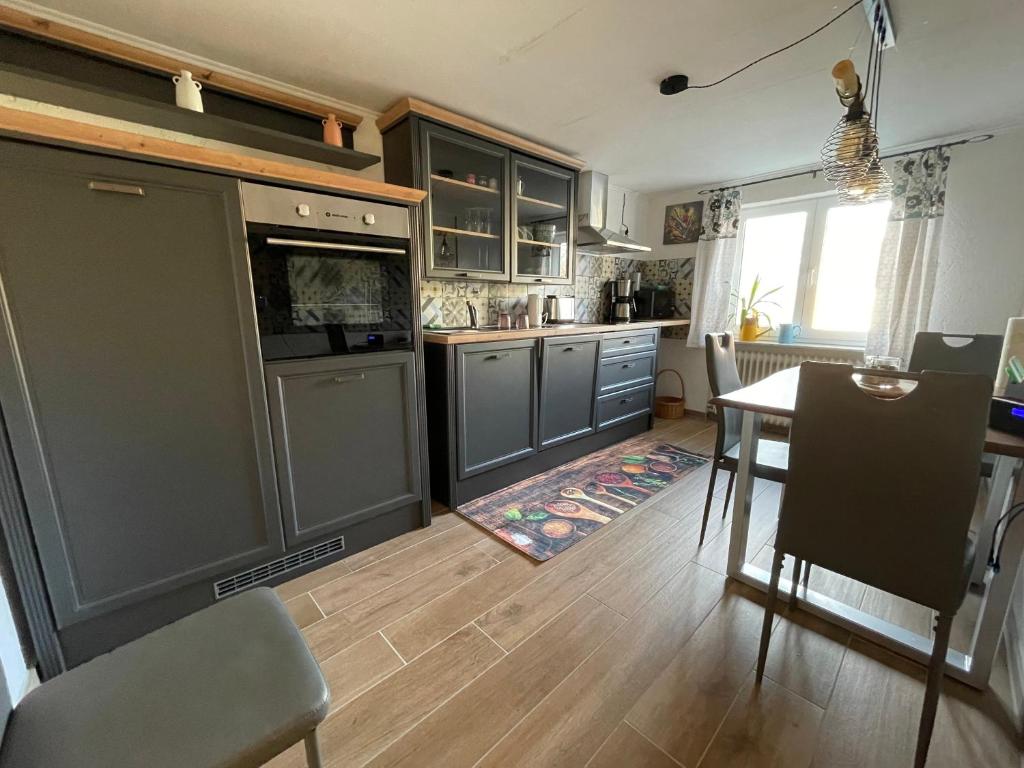 a kitchen with gray cabinets and a table and a dining room at Charmante Doppelhaushälfte in Tuttlingen