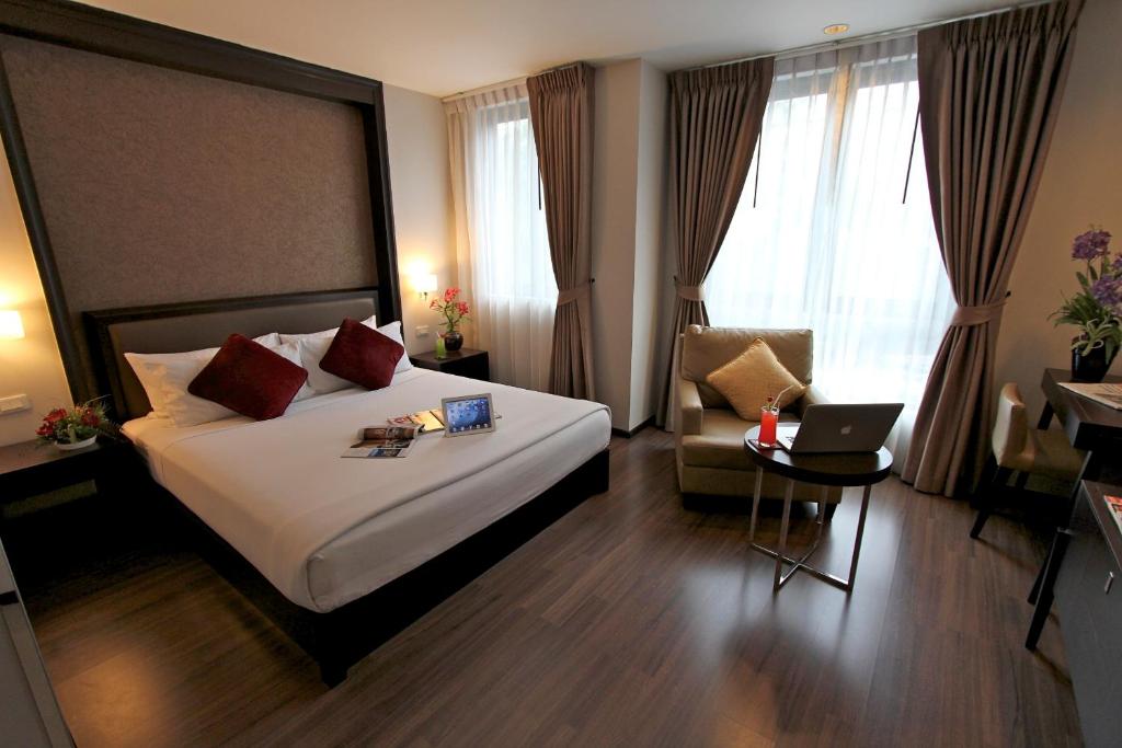 una camera d'albergo con un letto, una sedia e un computer portatile di The Dawin Hotel a Bangkok