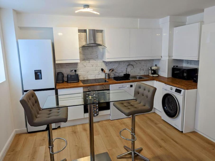 eine Küche mit weißen Schränken und einer Glasscheibe in der Unterkunft Thurrock-Grays Cosy 2 bed Flat easy access to London in Grays Thurrock