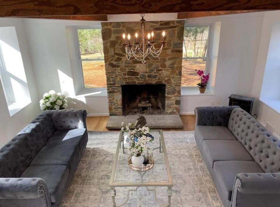a living room with two couches and a stone fireplace at Colonial Chic - 3BR home, VA wine country near Harpers Ferry in Purcellville