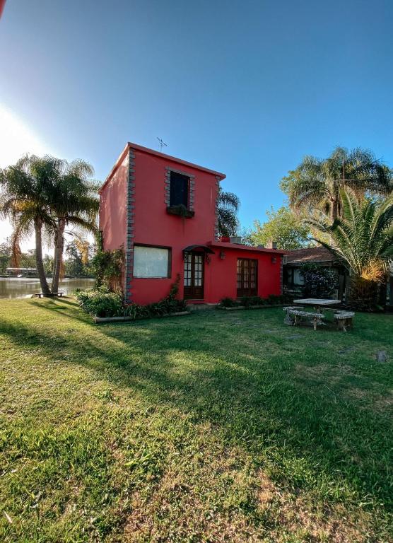 una casa roja en un campo con un patio en Complejo Laguna Chica en Dique Luján