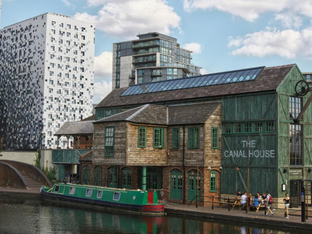 a building next to a river with a boat at Johal Accommodation Ltd- NEC 1 bedroom studio apartment with free parking in Sheldon