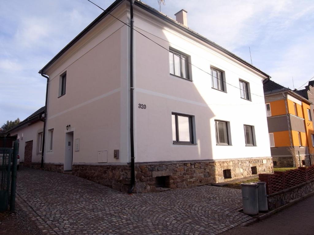 a white building on a street with a stone wall at Apartmány Pekárna in Staré Město