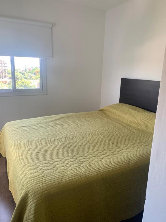 um quarto com uma cama com uma colcha amarela em Edificio Rey Niño em Posadas