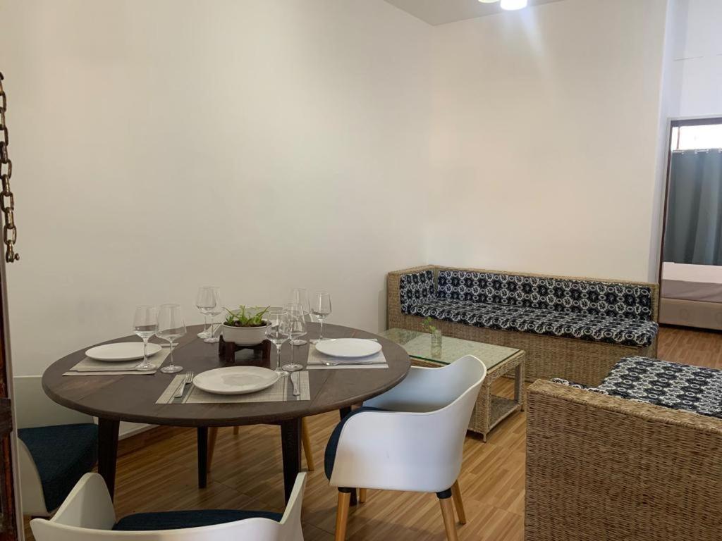 a dining room with a table and white chairs at Chambre Centre de Maputo in Maputo