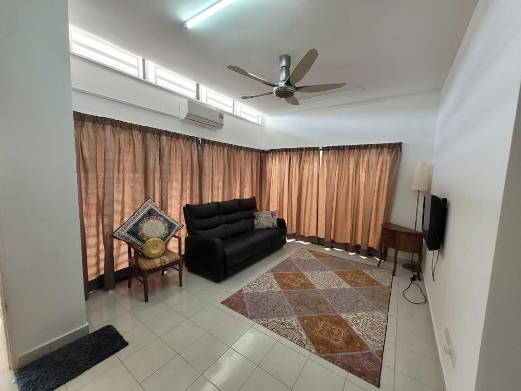 - un salon avec un canapé noir et un ventilateur de plafond dans l'établissement Che Ta Homestay for musliim only, à Kampong Geliga Besar