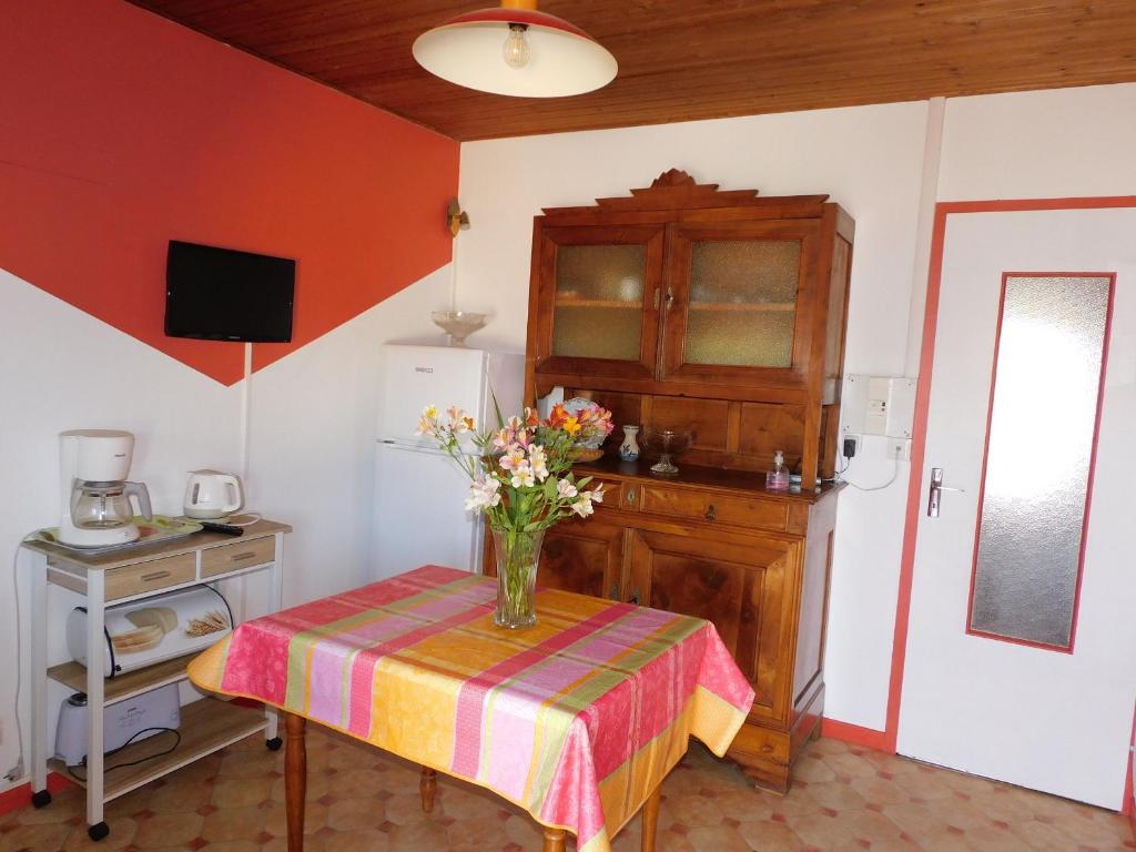 une cuisine avec une table avec un vase de fleurs dessus dans l'établissement Gîte rustique avec salle de jeux et animaux en campagne - FR-1-426-336, à Saint-Julien-des-Landes