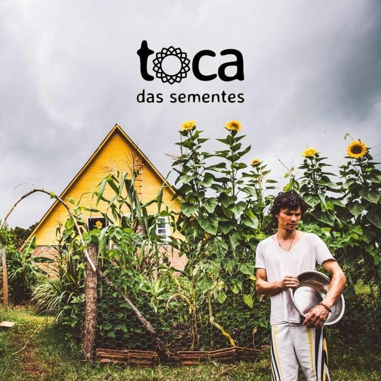 a man standing in front of a field of sunflowers at Toca das Sementes in Maria Preta