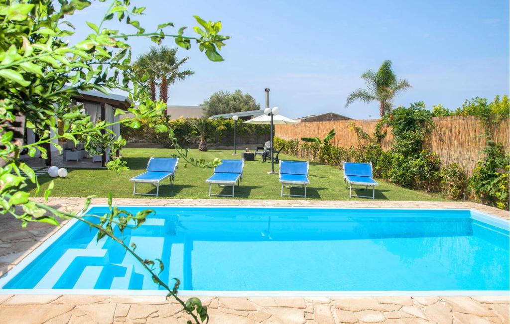 - une piscine avec des chaises bleues dans la cour dans l'établissement Nice Home In Scicli With Swimming Pool, à Scicli