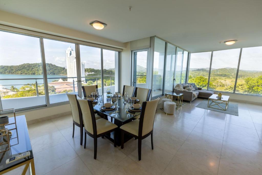 uma sala de jantar com mesa e cadeiras e janelas grandes em Lujoso apartamento Panama em ArraijÃ¡n