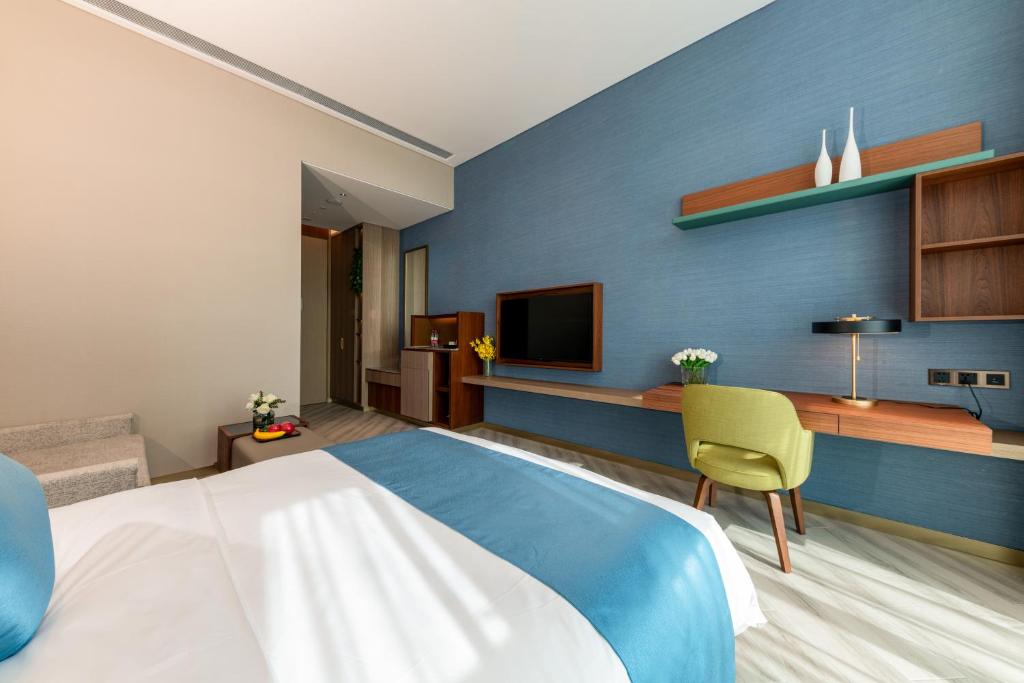 a bedroom with a large bed with a blue wall at Sha Zhi Ye Serviced Apartment Hotel - Houjie Wanda Plaza Liaoxia Subway Station in Dongguan