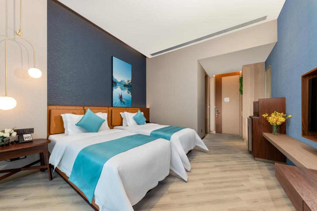 a bedroom with a large bed with blue walls at Sha Zhi Ye Serviced Apartment Hotel - Houjie Wanda Plaza Liaoxia Subway Station in Dongguan