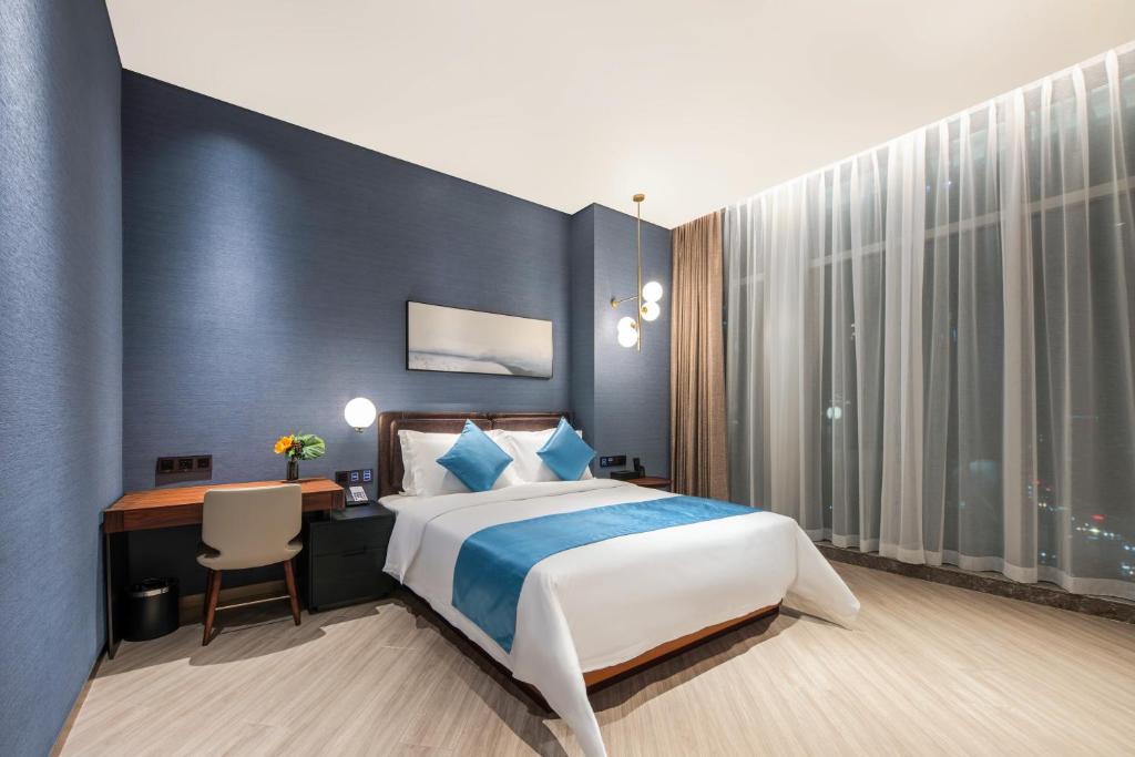 a hotel room with a bed and a desk and a desk at Sha Zhi Ye Serviced Apartment Hotel - Houjie Wanda Plaza Liaoxia Subway Station in Dongguan