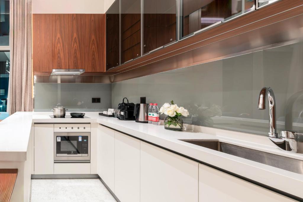 a kitchen with white cabinets and a sink at Sha Zhi Ye Serviced Apartment Hotel - Houjie Wanda Plaza Liaoxia Subway Station in Dongguan