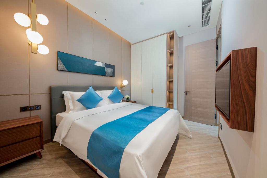 a bedroom with a large bed and a television at Sha Zhi Ye Serviced Apartment Hotel - Houjie Wanda Plaza Liaoxia Subway Station in Dongguan