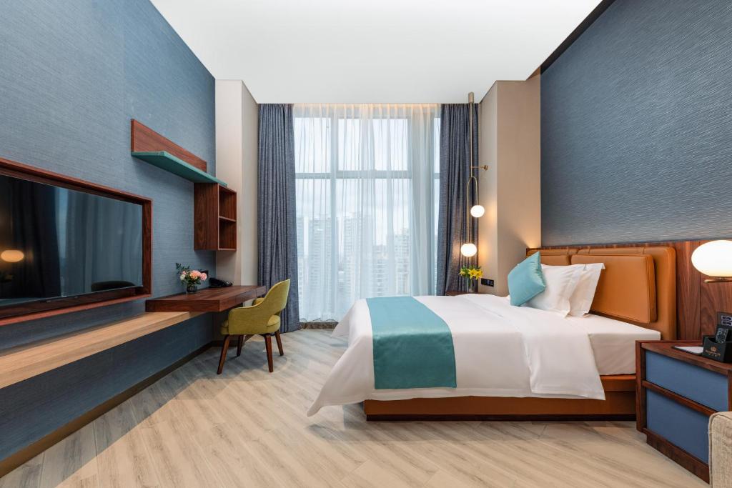 a hotel room with a bed and a tv at Sha Zhi Ye Serviced Apartment Hotel - Houjie Wanda Plaza Liaoxia Subway Station in Dongguan