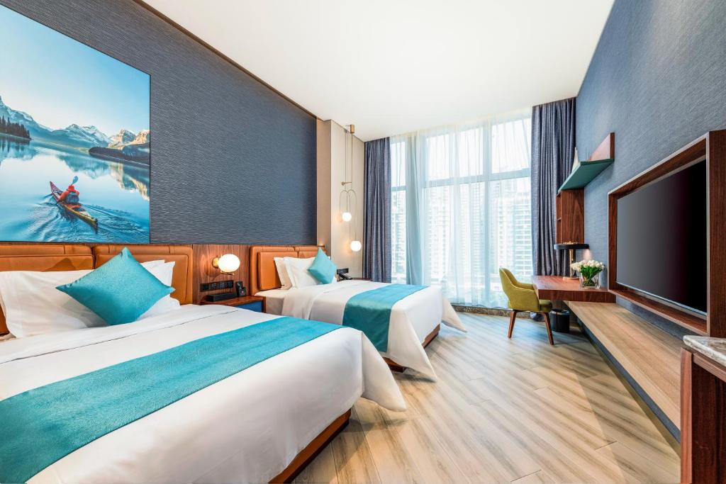 a hotel room with two beds and a flat screen tv at Sha Zhi Ye Serviced Apartment Hotel - Houjie Wanda Plaza Liaoxia Subway Station in Dongguan