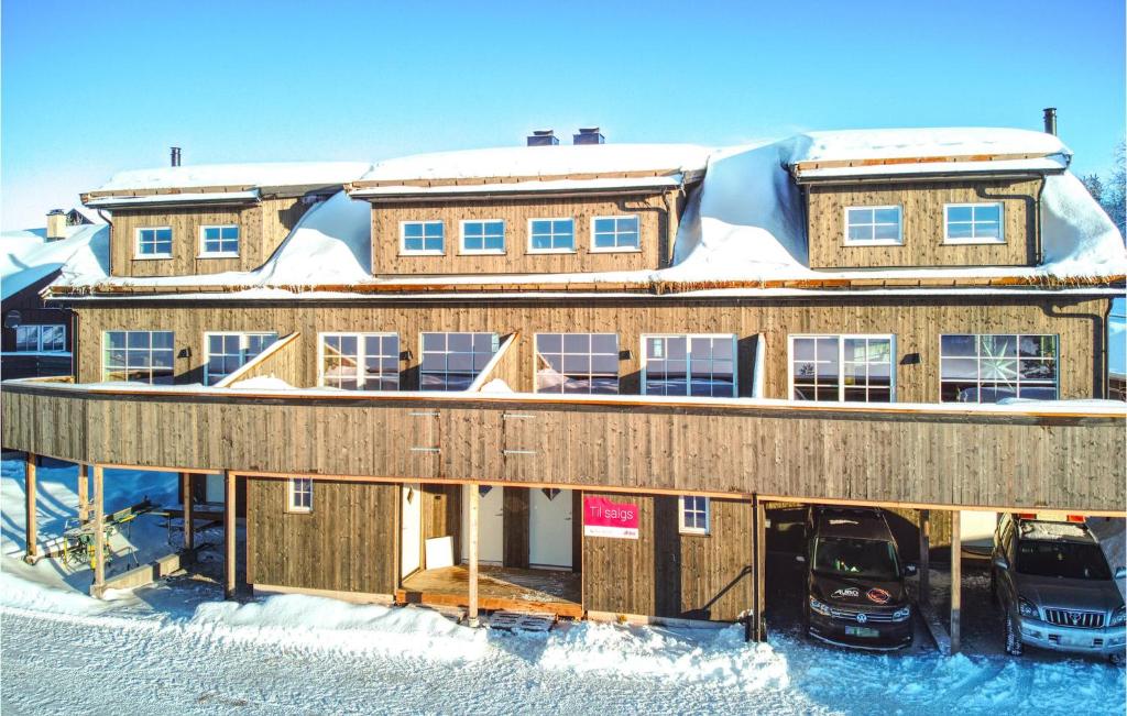 un bâtiment recouvert de neige avec deux voitures garées devant dans l'établissement Gorgeous Home In seral With Kitchen, à Åseral