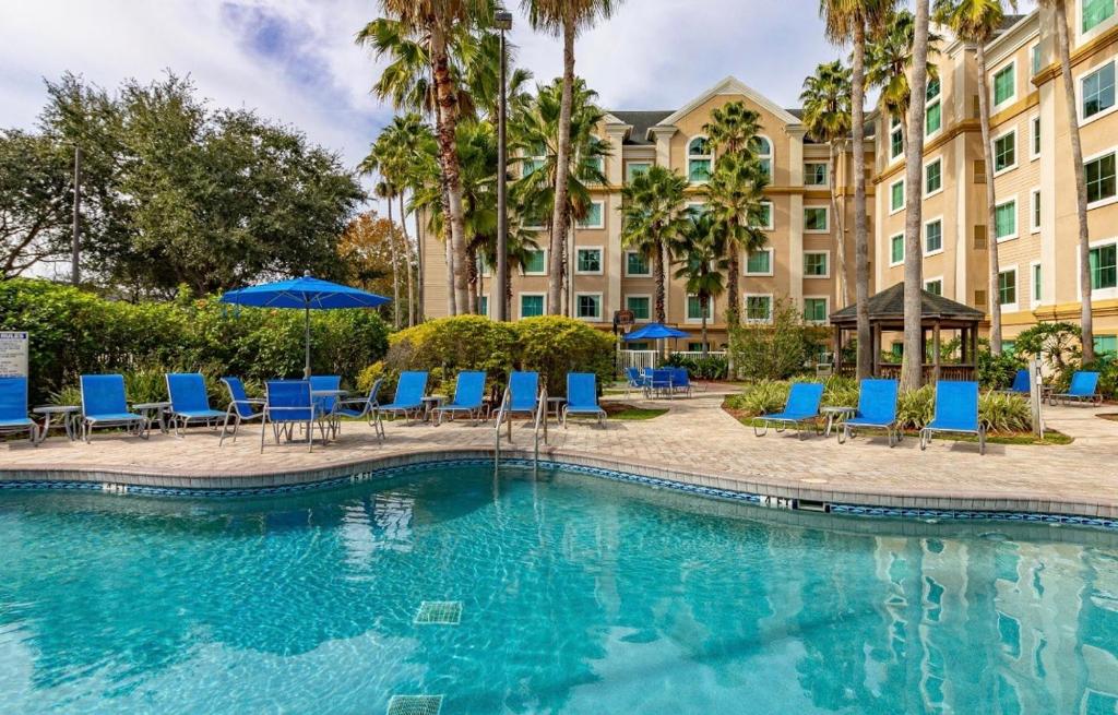 einem Pool mit Stühlen und Sonnenschirmen vor einem Gebäude in der Unterkunft Resort Hotel family Condo near Disney parks - Lake Buena Vista in Orlando