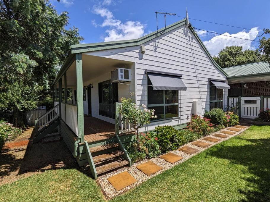 ein weißes Haus mit einer Veranda und einem Hof in der Unterkunft Buninyong Country Cottage in Buninyong