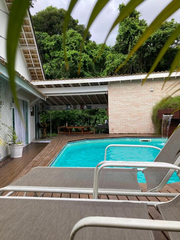 a swimming pool with lounge chairs next to a house at Pouso Costa do Sol in Bertioga