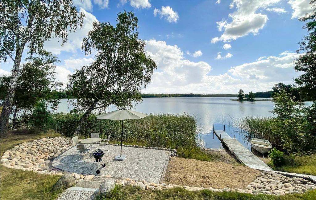un patio con una mesa y una sombrilla junto a un lago en 2 Bedroom Lovely Home In Vaggeryd, en Vaggeryd