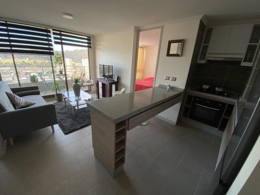 a kitchen and living room with a large counter top at Hermoso Departamento con excelente vista, a pasos de la Quinta Vergara, cercano a Reloj de Flores y Playa Caleta Abarca in Viña del Mar