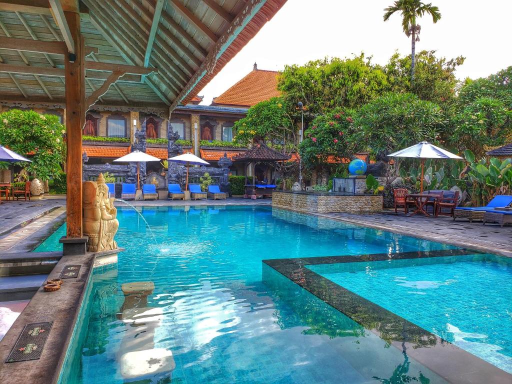 a large swimming pool in a resort with umbrellas at Satriya Cottages in Kuta