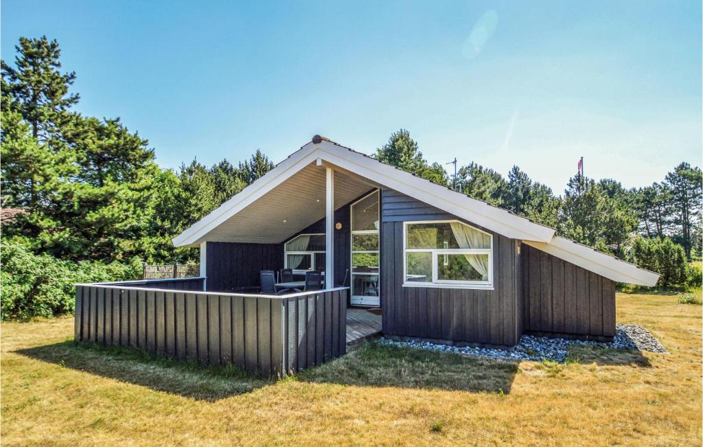 a small house with a pitched roof on a field at Three-Bedroom Holiday Home In Rodby in Rødby