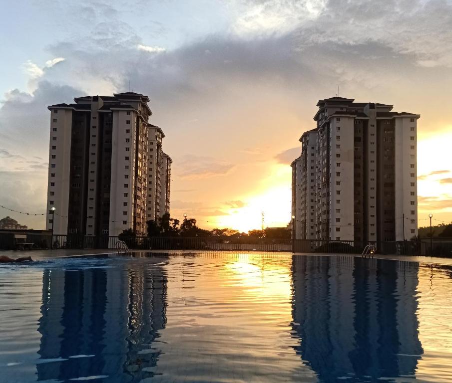 two tall buildings with the sunset in the background at Suria Kipark Damansara 3R2B 950sq ft Apartment in Kuala Lumpur