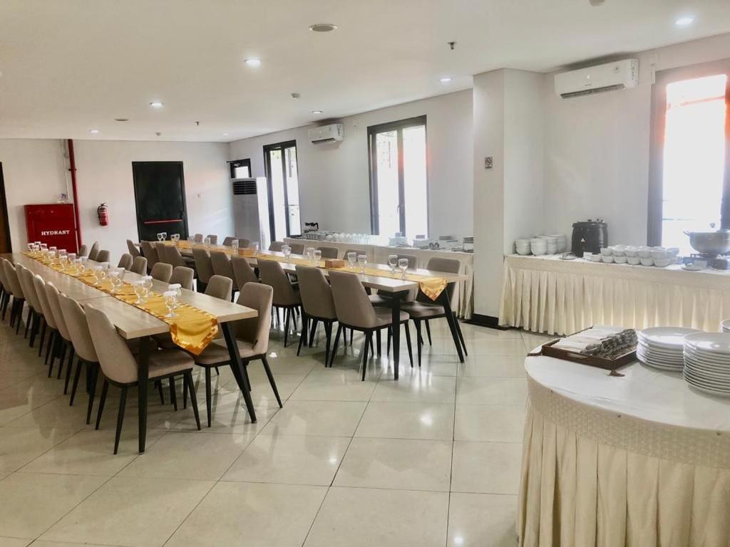 AZKA HOTEL Managed by Salak Hospitality في جاكرتا: غرفة طعام مع طاولات وكراسي وبار