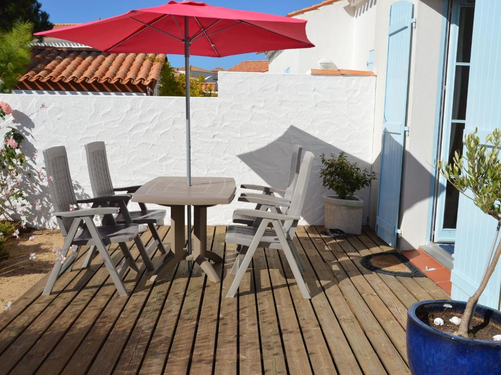 une table, des chaises et un parasol sur une terrasse dans l'établissement Maison 6 pers, terrasse sur plan d'eau, proche plage, golf, centre et commodités - FR-1-323-474, à Saint-Jean-de-Monts