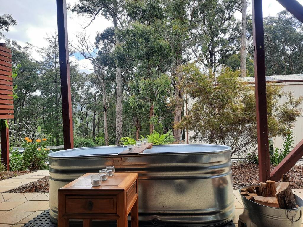 una bañera de hidromasaje en un patio con vistas a los árboles en Cock or Two Kink House, en Cockatoo