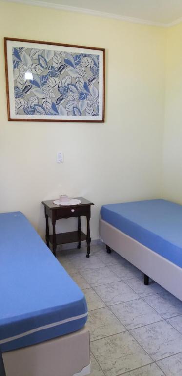 a room with two beds and a table at Apartamento Praia Massaguaçú in Caraguatatuba