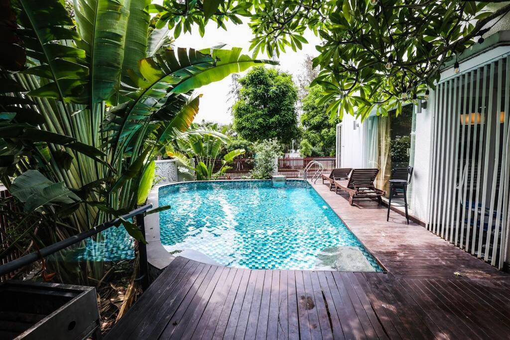a swimming pool on a wooden deck next to a house at Maison Villa Orchid Phú Mỹ Hưng in Ho Chi Minh City