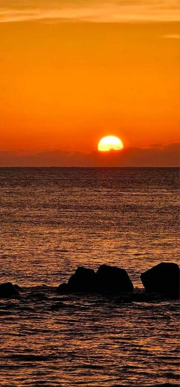 a sunset over the ocean with rocks in the water at 5 Loaves 2 Fish B&amp;B in Hualien City