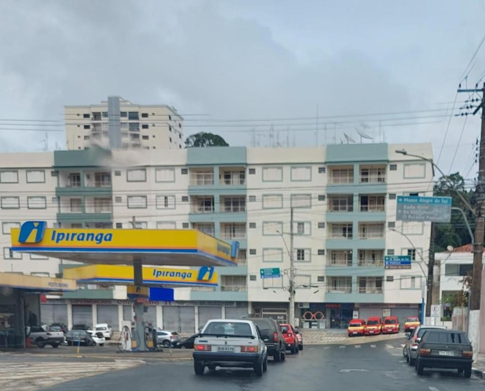 a gas station with cars parked in front of a building at Apartamento Aconchegante Centro Serra Negra in Serra Negra