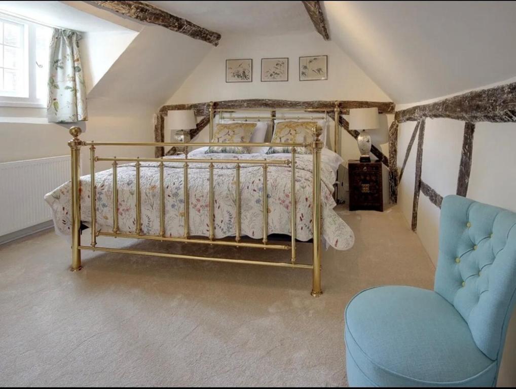 ein Schlafzimmer mit einem Bett und einem blauen Stuhl in der Unterkunft Eglantine in Crondall