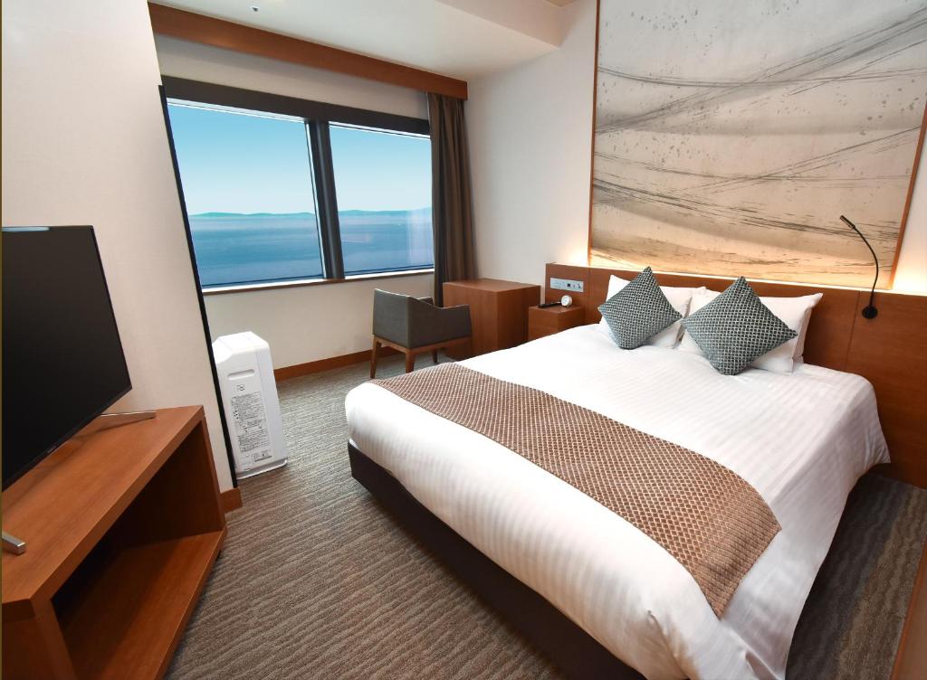 a hotel room with a bed and a flat screen tv at Odysis Suites Osaka Airport Hotel in Izumi-Sano
