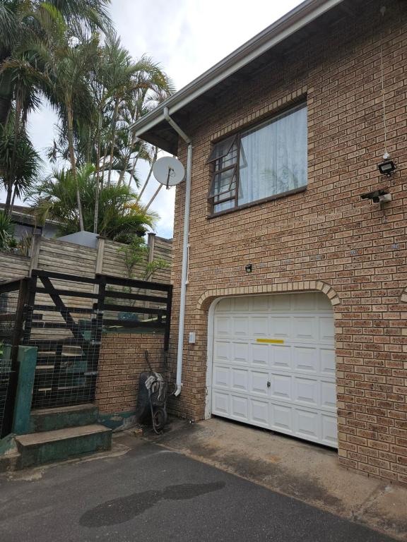 a brick house with a white garage door at Kiaatplace Holiday Apartment in Kingsburgh
