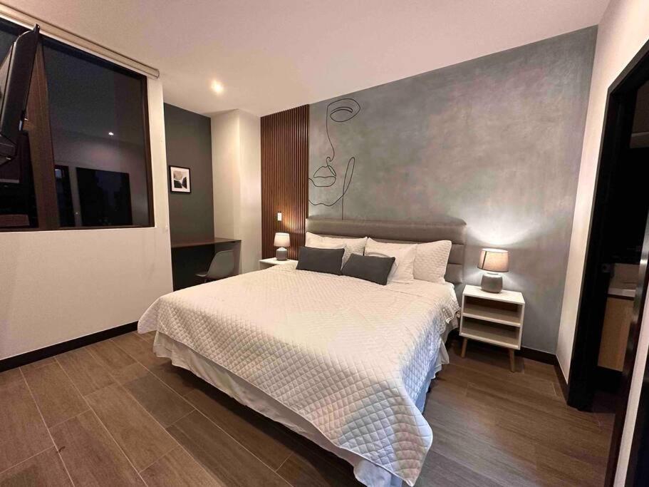 sypialnia z dużym białym łóżkiem i telewizorem w obiekcie New Modern Apartment near Mall w mieście Gwatemala