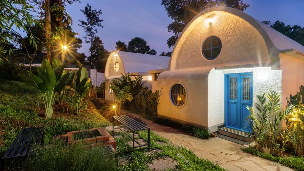 a small house with a blue door in a yard at Aphrodite Homestays Coorg by The Almanac in Napoklu