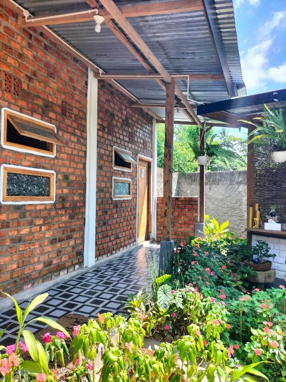 an outdoor patio with a brick building and flowers at AZALEA GARDEN HOMESTAY in Pagaralam