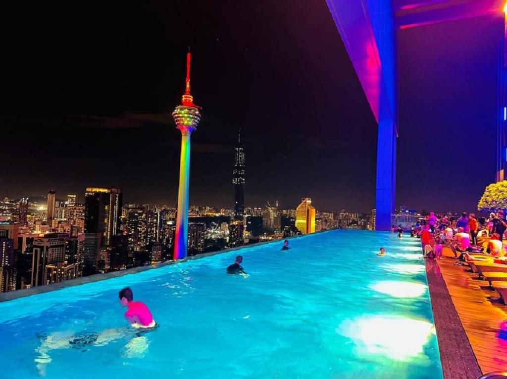 a group of people swimming in a infinity pool at night at PLATINUM Suites KLCC By AR Hospitality in Kuala Lumpur