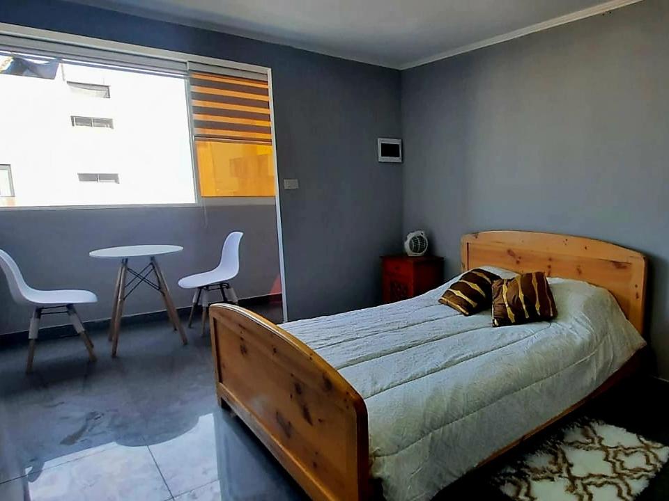 a bedroom with a bed and a table with chairs at Departamento a pasos de la playa in Iquique